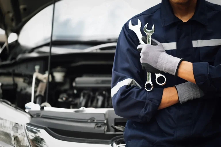 Mechanic holding two wrenches open hood